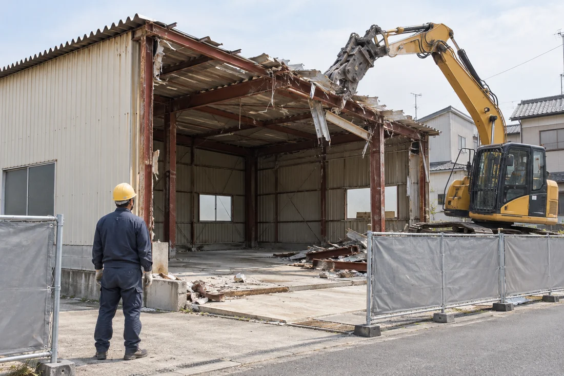 中の片付けを済ませた小規模な建物を重機で解体する様子